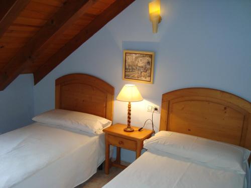 1 dormitorio con 2 camas y una lámpara en una mesa en Apartamentos Saila, en Castejón de Sos