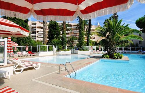 - une piscine avec des parasols et des chaises ainsi qu'une piscine dans l'établissement Appartement de la Résidence du Golfe, au Golfe-Juan