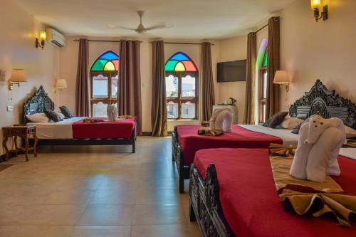 a bedroom with three beds and stained glass windows at Tembo Palace Hotel in Zanzibar City