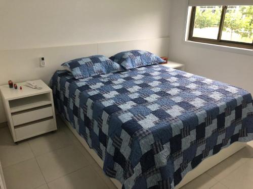 um quarto com uma cama azul e branca e uma mesa de cabeceira em Flat Carneiros Beach Resort em Praia dos Carneiros