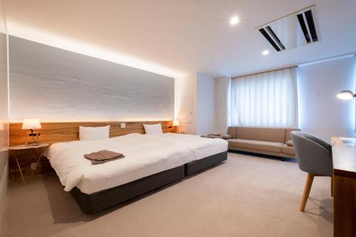 Hukue的住宿－SERENDIP HOTEL GOTO，卧室配有一张白色的大床和一张沙发。