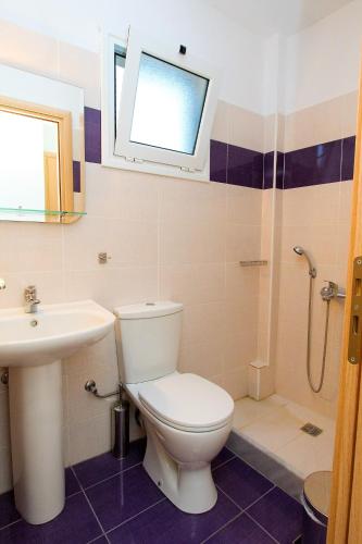 a bathroom with a toilet and a sink and a window at Evita's Studios in Loutra Edipsou
