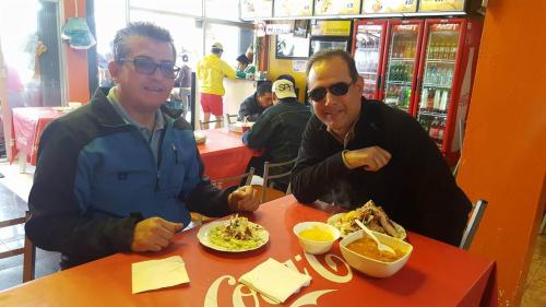 two men sitting at a table eating food at Casa de Mármol in Riobamba