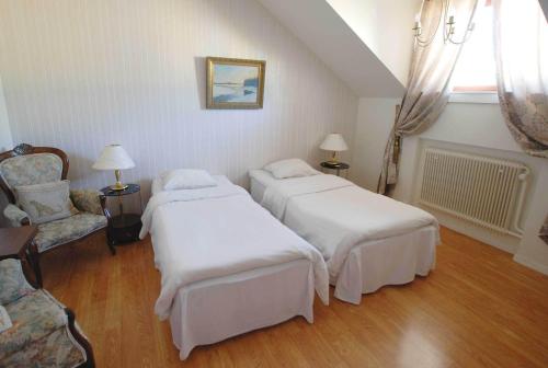 a hotel room with two beds and a chair at Avesta Stadshotell in Avesta