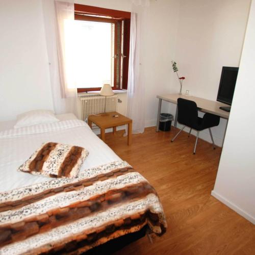 a bedroom with a bed and a desk with a computer at Avesta Stadshotell in Avesta