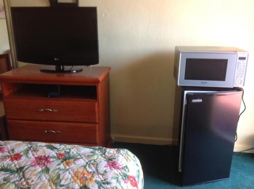 a room with a tv and a dresser with a microwave at Sunshine Inn of Daytona Beach in Daytona Beach