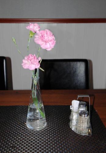 a glass vase with pink flowers on a table at Avesta Stadshotell in Avesta