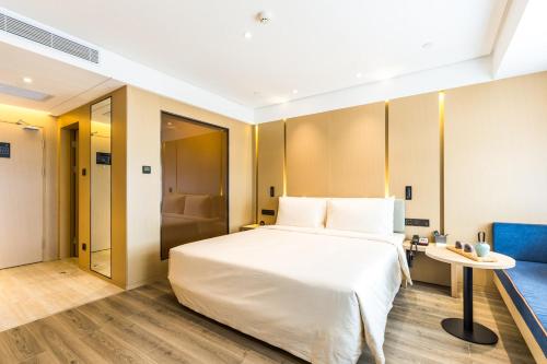 a bedroom with a large white bed and a table at Atour Yan'an Zaoyuan Hotel in Yan'an