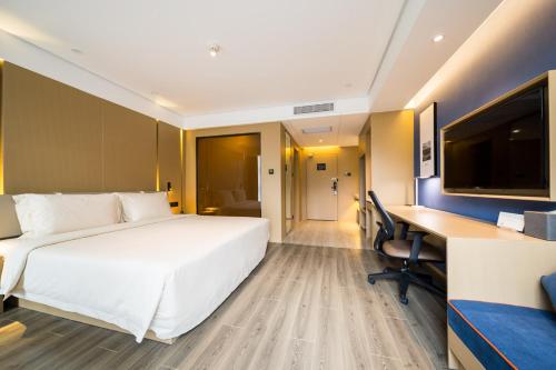 a hotel room with a large white bed and a desk at Atour Yan'an Zaoyuan Hotel in Yan'an