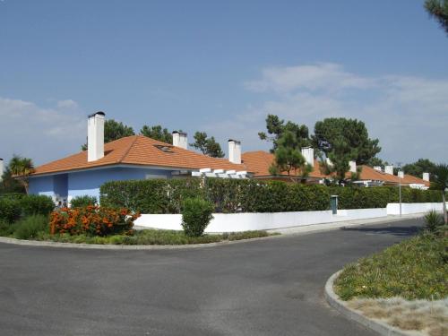 a house with a white fence next to a street at Aldeamento Turistico Casas da Comporta in Comporta