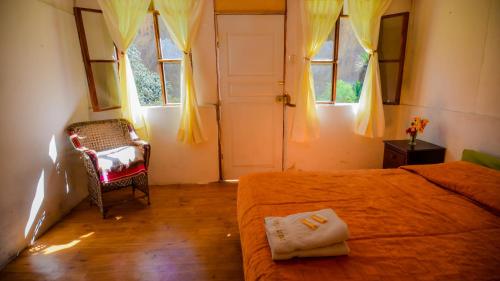 Schlafzimmer mit einem Bett, einem Stuhl und Fenstern in der Unterkunft Tropical Lodge in Cabanaconde