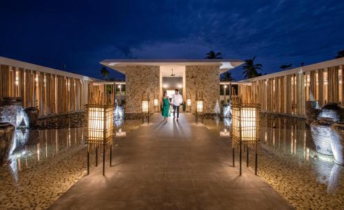 a couple walking down the aisle of a resort at night at Emerald Maldives Resort & Spa-Deluxe All Inclusive in Raa Atoll
