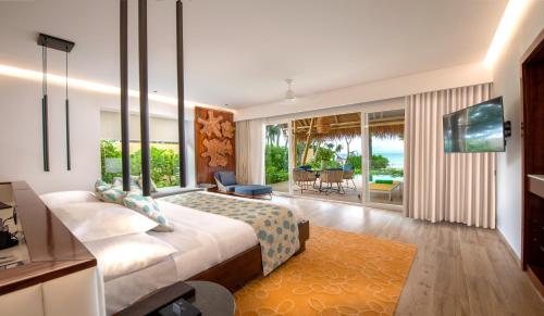 a bedroom with a large bed and a living room at Emerald Maldives Resort & Spa-Deluxe All Inclusive in Raa Atoll
