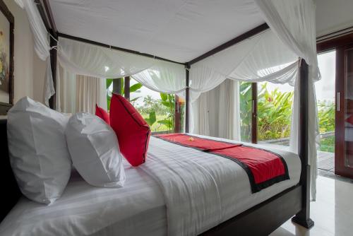 a bedroom with a white bed with red pillows at Villa Cendrawasih Ubud in Tegalalang