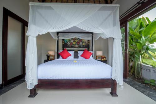 a bedroom with a canopy bed with red pillows at Villa Cendrawasih Ubud in Tegalalang