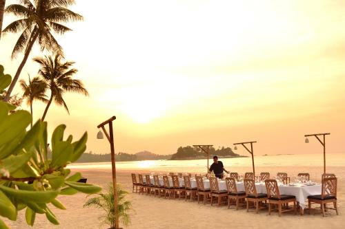 a man standing on a beach with a table and chairs at The Sanchaya in Lagoi