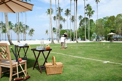 a man playing a game of golf in a field with palm trees at The Sanchaya in Lagoi
