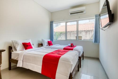 two beds in a room with a tv on the wall at RedDoorz near Ciputra World 3 in Surabaya
