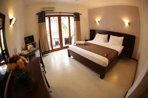 a bedroom with a large bed and a window at Hotel Shanelo in Negombo
