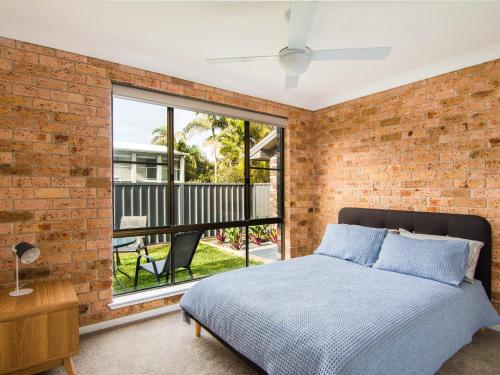 een slaapkamer met bakstenen muren, een bed en een raam bij 40 Underwood Road in Forster