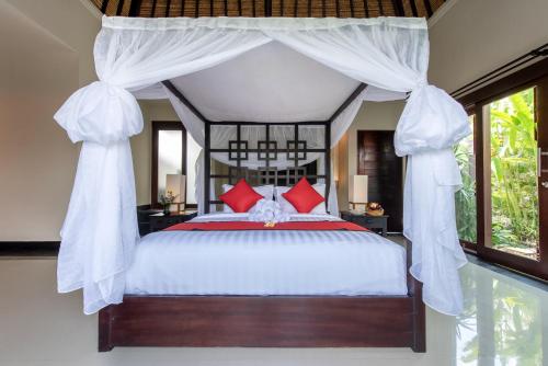 a bedroom with a canopy bed with red pillows at Villa Cendrawasih Ubud in Tegalalang
