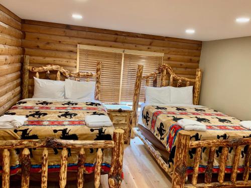 two beds in a room with wooden walls at Heart Six Ranch in Moran