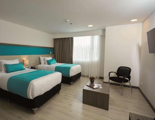a hotel room with two beds and a chair at Hotel Nivari Duitama in Duitama