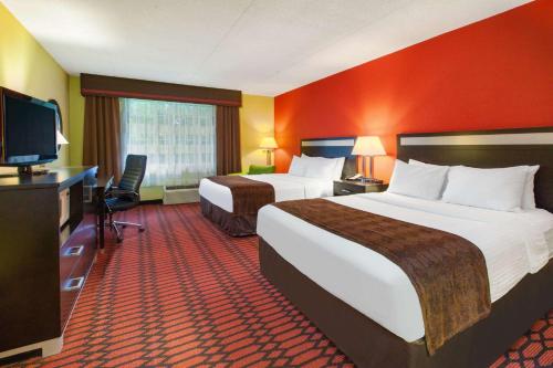 Habitación de hotel con 2 camas y TV de pantalla plana. en Baymont by Wyndham Harrisburg en Harrisburg