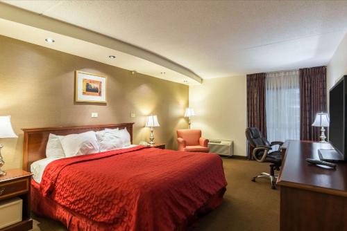 Habitación de hotel con cama roja y escritorio. en Plaza Inn & Suites, en Hagerstown