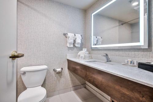 a bathroom with a toilet and a sink and a mirror at Comfort Inn & Suites South in Calgary