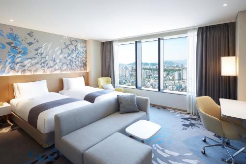 a hotel room with two beds and a couch at Novotel Suites Ambassador Seoul Yongsan in Seoul