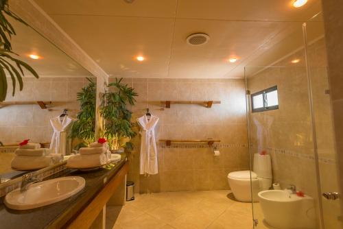 a bathroom with two sinks and a shower and a toilet at Coco de Mer Hotel and Black Parrot Suites in Grand'Anse Praslin