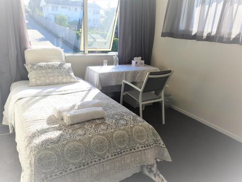 a bedroom with a bed and a table and a chair at Sylvia Park House in Auckland