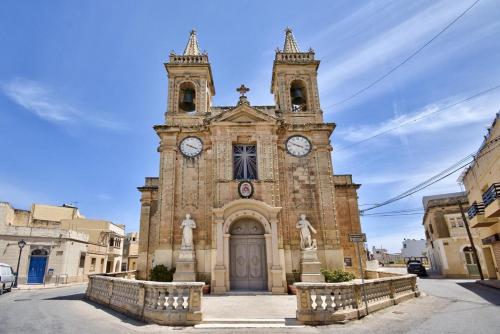 an old building with a clock tower in a city at Private village apartment in Kirkop