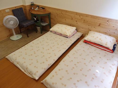 two beds in a room with a chair and a fan at Ho Hai Yan Homestay in Chenggong