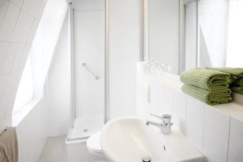 een witte badkamer met een wastafel en een douche bij Pension Villa Nordland in Bad Kissingen