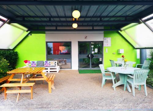 eine Terrasse mit Tischen und Stühlen und einer grünen Wand in der Unterkunft Lemon Hotel Ch Futuroscope in Châtellerault