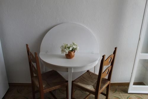 a table with chairs and a vase with flowers on it at Residenza Gherly in Capo Vaticano