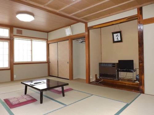 a living room with a table and a tv at Togakushi- Kogen Minshuku Rindo in Nagano