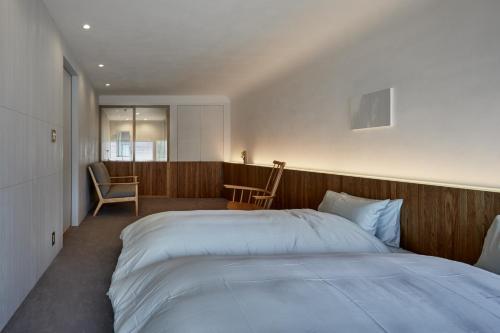 um quarto com uma grande cama branca e uma cadeira em 滔々 御崎 二階の宿 toutou Onzaki Nikai no Yado em Kurashiki