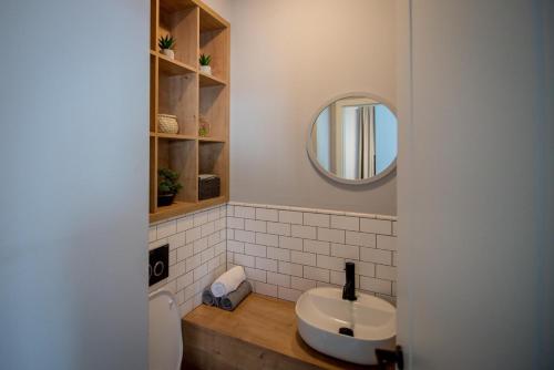 uma casa de banho com um lavatório branco e um espelho. em The Aviator Apartment - Jacuzzi & Panoramic View em Cluj-Napoca