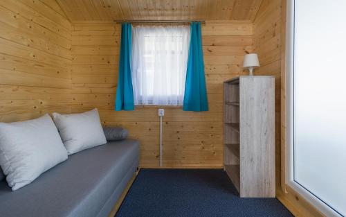 a room with a bed and a window with blue curtains at Biała Wioska 2 in Ustronie Morskie