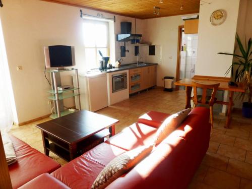 ein Wohnzimmer mit einem roten Sofa und einer Küche in der Unterkunft Ferienwohnung Bösch in Taching am See