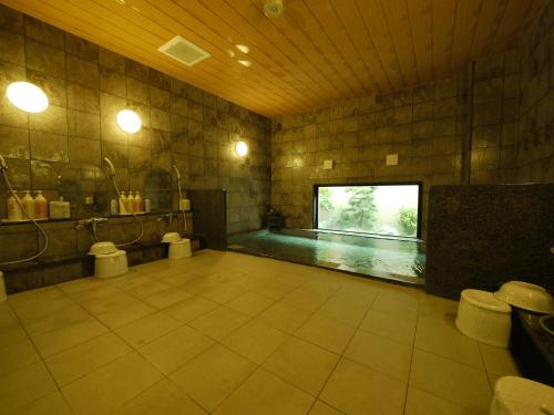 a large bathroom with a swimming pool with two toilets at Hotel Route-Inn Uozu in Uozu