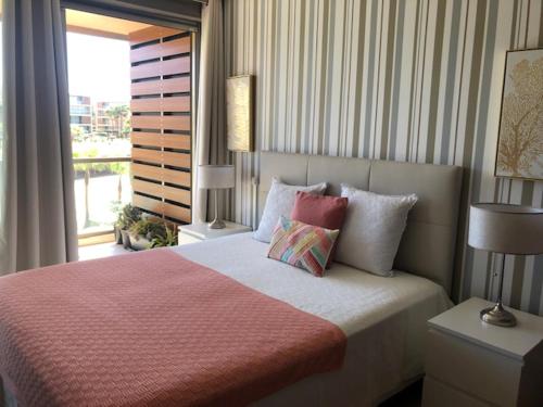 una camera da letto con letto, cuscini e finestra di Herdade dos Salgados - Beach House ad Albufeira