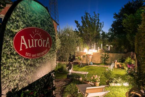 a sign on the side of a house with a garden at Bed and Breakfast Aurora in Sarzana
