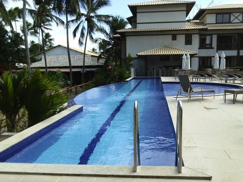 una gran piscina azul frente a una casa en Apartamento Enseada Praia do Forte, en Praia do Forte