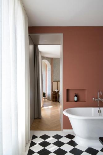 a bathroom with a white tub and a checkered floor at VillaVerde Aparthotel in Lagundo