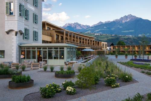 a hotel with a courtyard with benches and flowers at VillaVerde Aparthotel in Lagundo