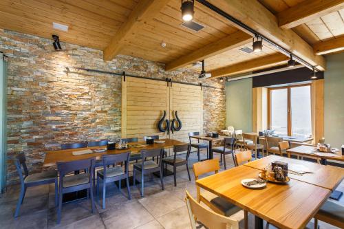 a restaurant with wooden tables and chairs and a brick wall at Restaurace a penzion Pod Lipami Metylovice in Metylovice